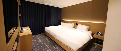 A hotel room with a large bed, a desk with a chair, a TV, and a telephone.