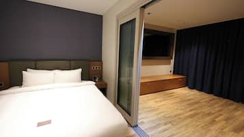A hotel room with a bed, bedside table, and a large window with curtains.