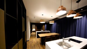 A modern kitchen with a central island, pendant lighting, and a dark blue curtain backdrop. - Sea Cruise Hotel (Sokcho)
