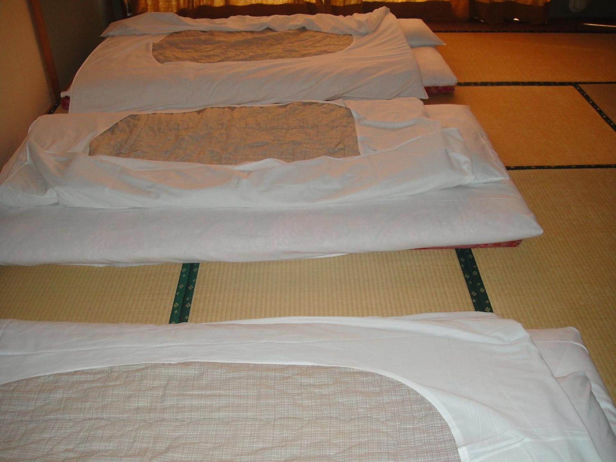 Una habitación con esteras de tatami y futones dispuestos para dormir.