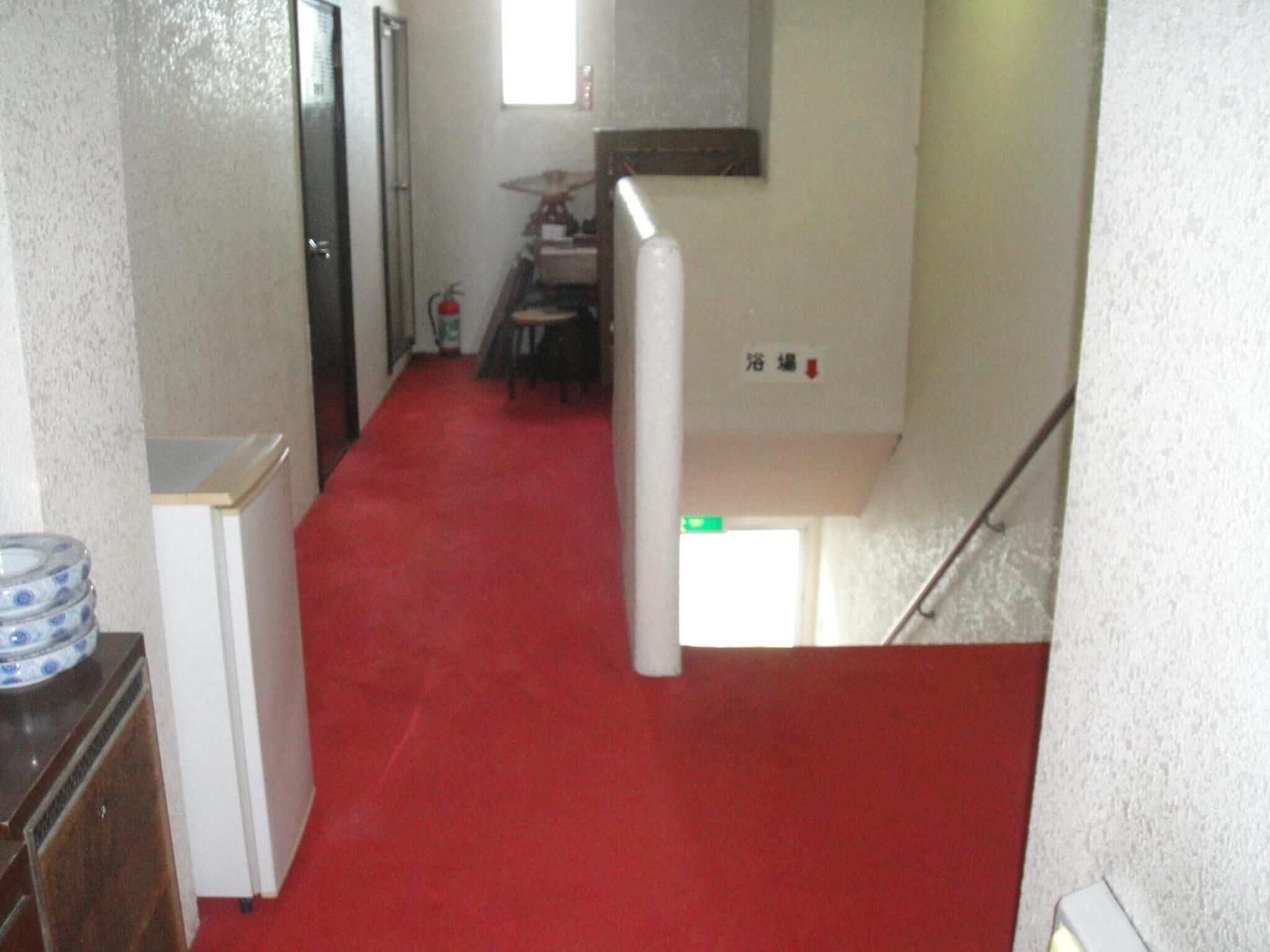 A narrow hallway with a red carpet leading to a staircase.