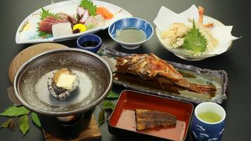 A variety of Japanese dishes including sashimi, grilled fish, and shrimp, served on different plates and bowls.