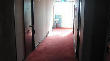 A corridor with carpeted floors, doors on both sides, and a visible exit sign.