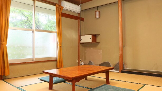 Una habitación japonesa tradicional con suelo de tatami, una mesa de madera y un puertas correderas.