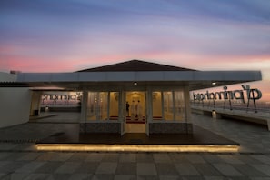 Un bâtiment moderne avec une entrée en verre, un tapis rouge et une enseigne ornée d’un logo.