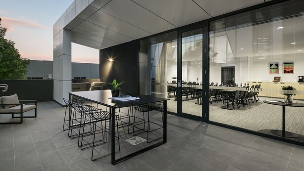 A modern outdoor seating area with a table and chairs, a sofa, and a potted plant. - Quest Notting Hill (Notting Hill)
