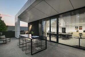 A modern outdoor seating area with a table and chairs, a sofa, and a potted plant. - Quest Notting Hill (Notting Hill)