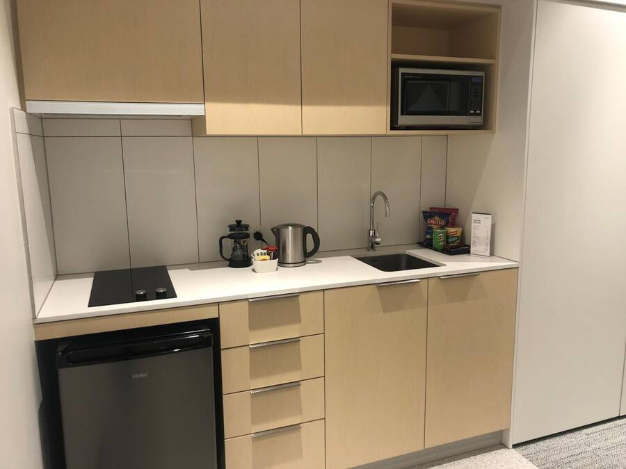 A compact kitchen with a dishwasher, a microwave, a coffee maker, and a sink.