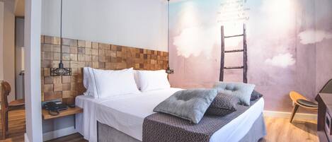 A modern bedroom with a wooden headboard, a bed with white linens, a bedside table with a lamp, and a wall mural.