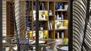 Una biblioteca moderna con estanterías de madera, un globo terráqueo y varios libros. Hay sillas y mesas en primer plano.