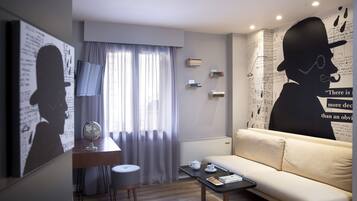 Uma sala de estar moderna com sofá, mesa de centro, escrivaninha e um grande mural na parede.