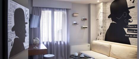 Una sala de estar moderna con un sofá, una mesa de centro, un escritorio y un mural grande en la pared.