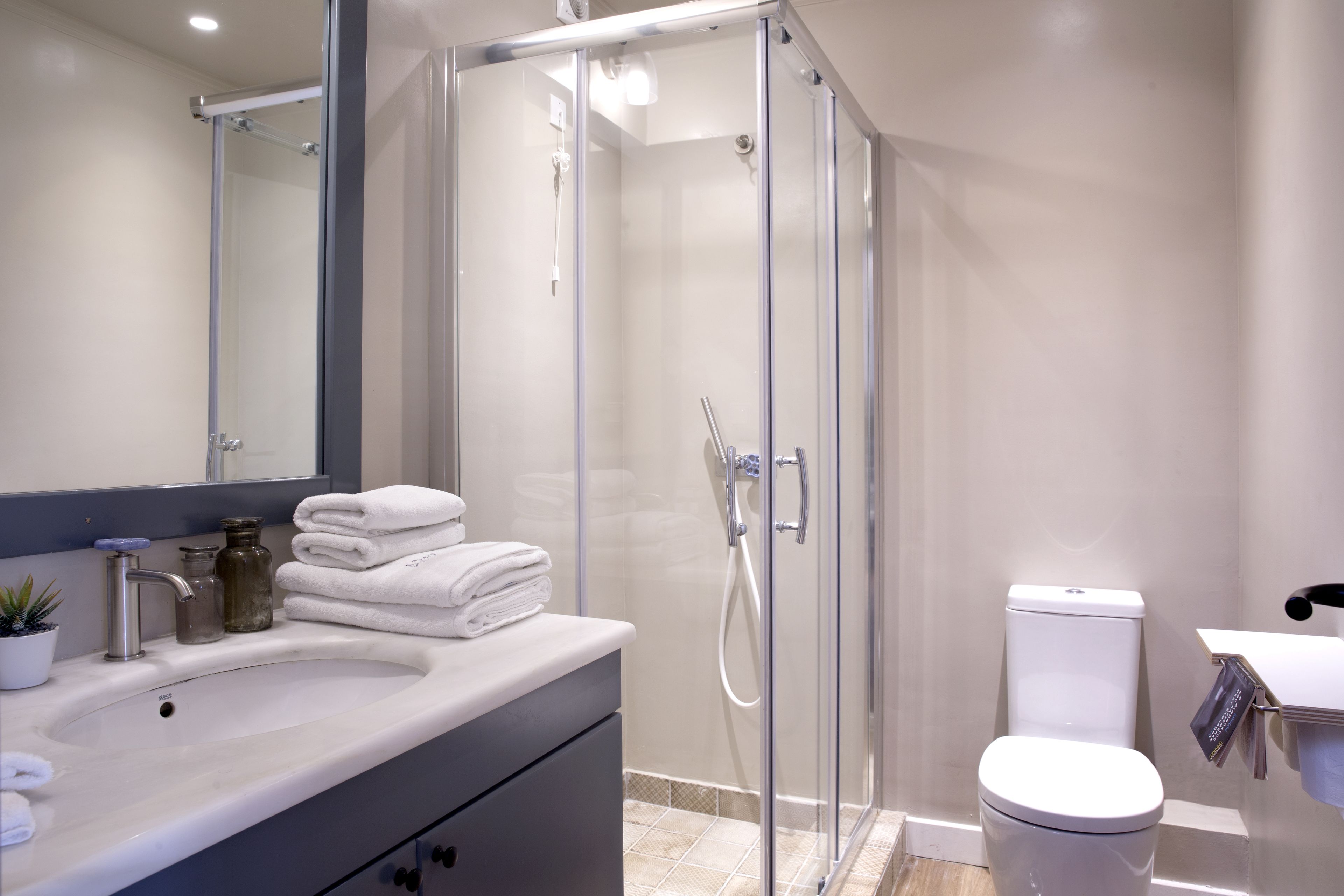 Een moderne badkamer met een douchecabine van glas, een wit wastafelmeubel en een toilet.