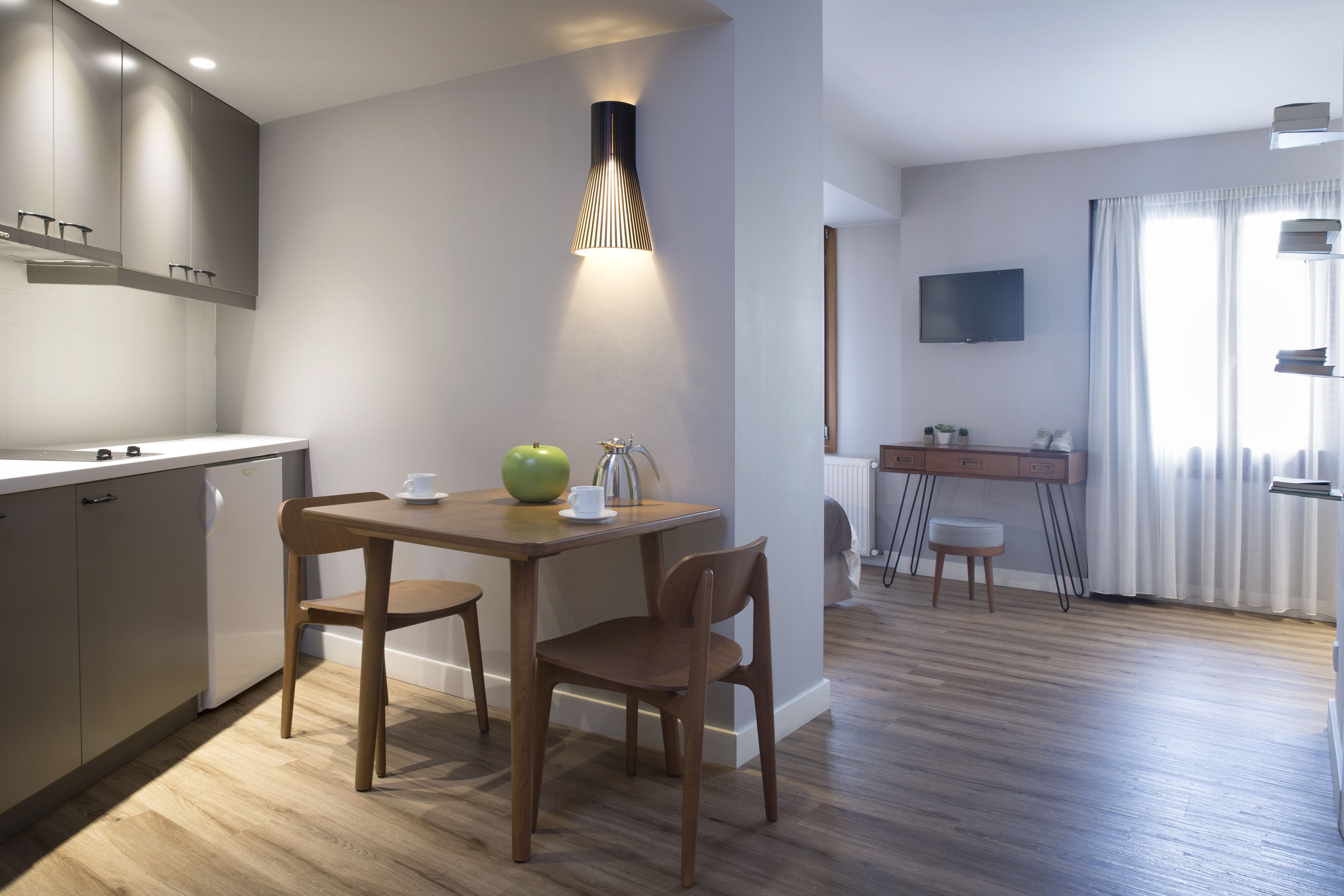 Une cuisine moderne avec des meubles de rangement en bois, une table à manger avec des chaises et un luminaire suspendu.