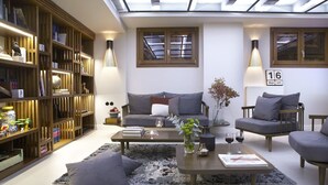 Una sala de estar moderna con tragaluces, una estantería, un conjunto de sofás y una mesa de centro.