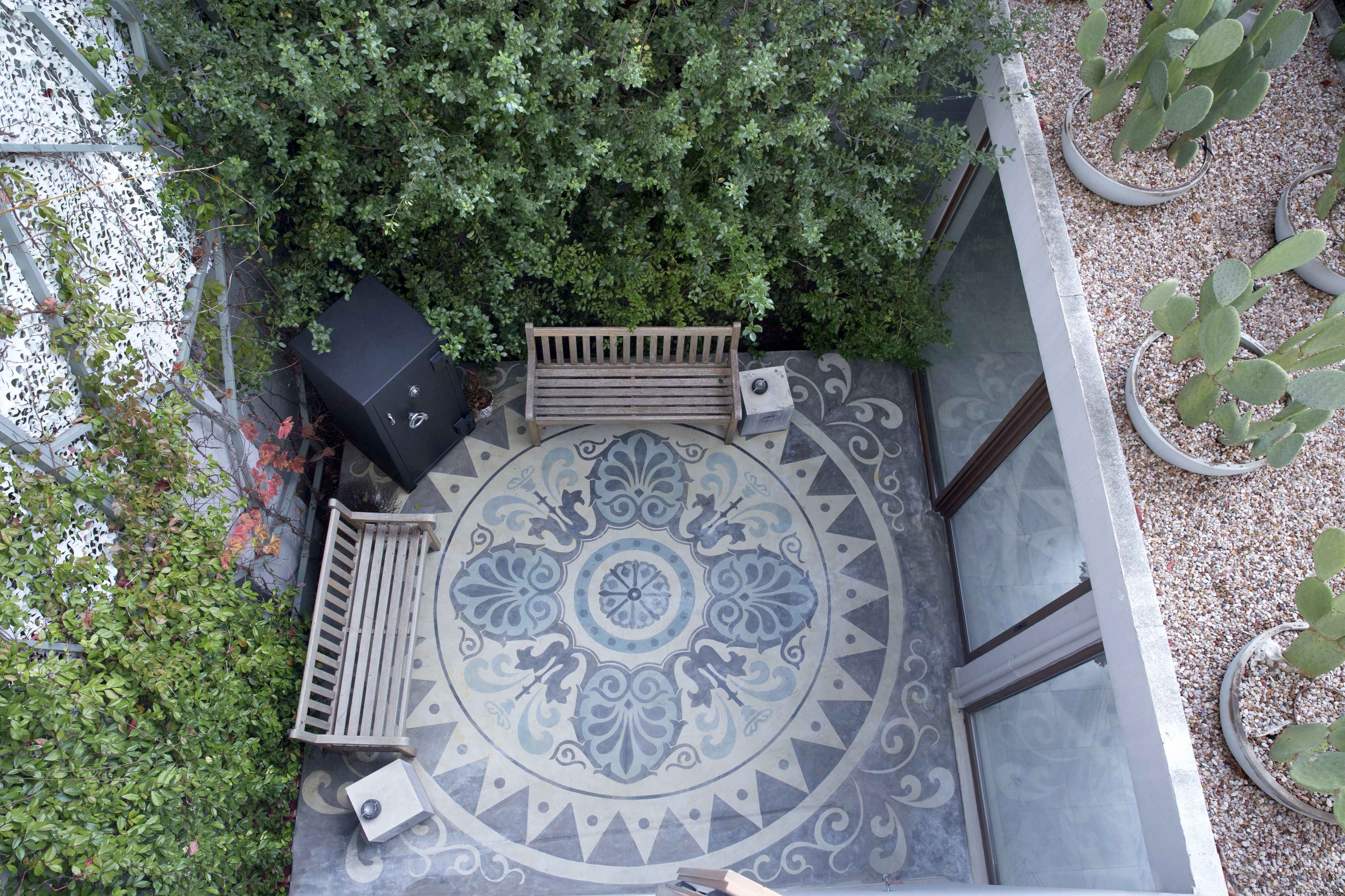 An outdoor patio with a circular patterned floor, a wooden bench, and potted cacti.