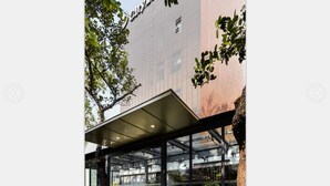 A modern building with a glass facade, a metal roof structure, and trees in the foreground. - City Inn OCT Loft Branch (Shenzhen)