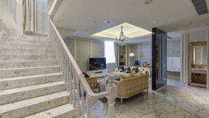 A spacious living area with a marble staircase, a television, and a chandelier. - City Inn OCT Loft Branch (Shenzhen)