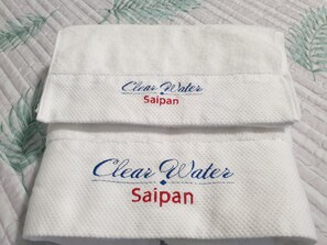 Two folded white towels with embroidered text "Clear Water Saipan". - Clear Water Hotel (Saipan)