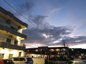 Un edificio de varios pisos con balcones y un estacionamiento.