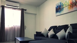 Ein modernes Wohnzimmer mit einem dunkelgrauen Sofa, einem Couchtisch und einem Gemälde an der Wand.