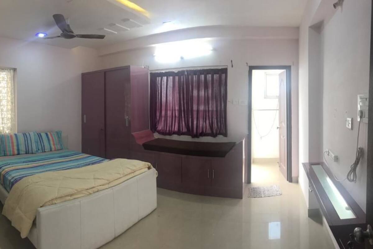 Ein Schlafzimmer mit Bett, Kleiderschrank, Schminktisch und Deckenventilator.