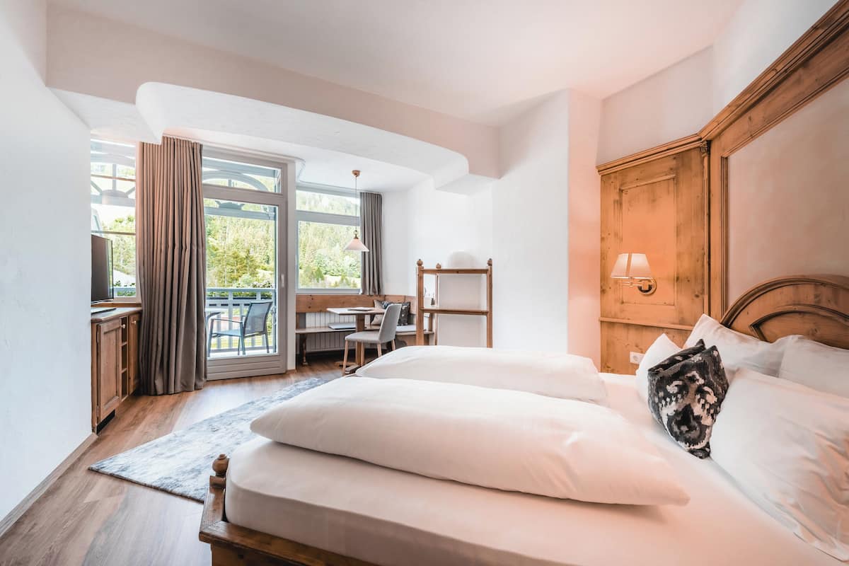 A bedroom with a large bed, a desk, and a chair near a window with curtains.