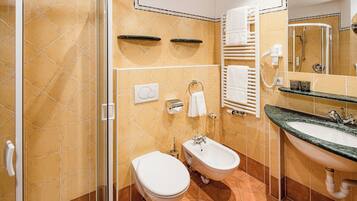 A bathroom with a shower, toilet, bidet, and sink.