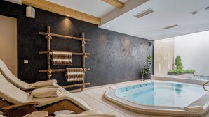 Et spaområde med jacuzzi, liggestole og en træreol med håndklæder.