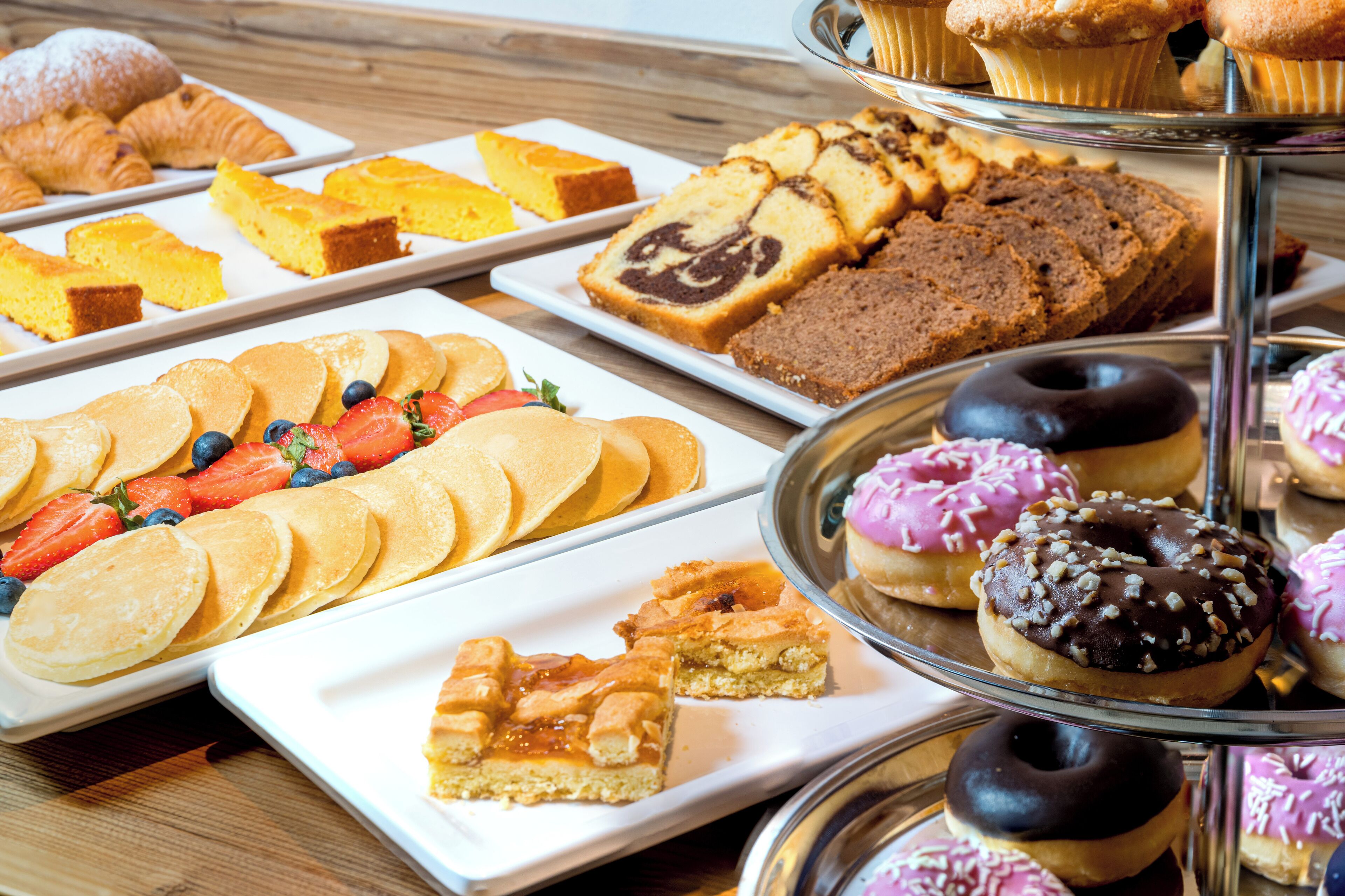 Una variedad de opciones para el desayuno, incluyendo bollería, muffins y donas, en una presentación escalonada.