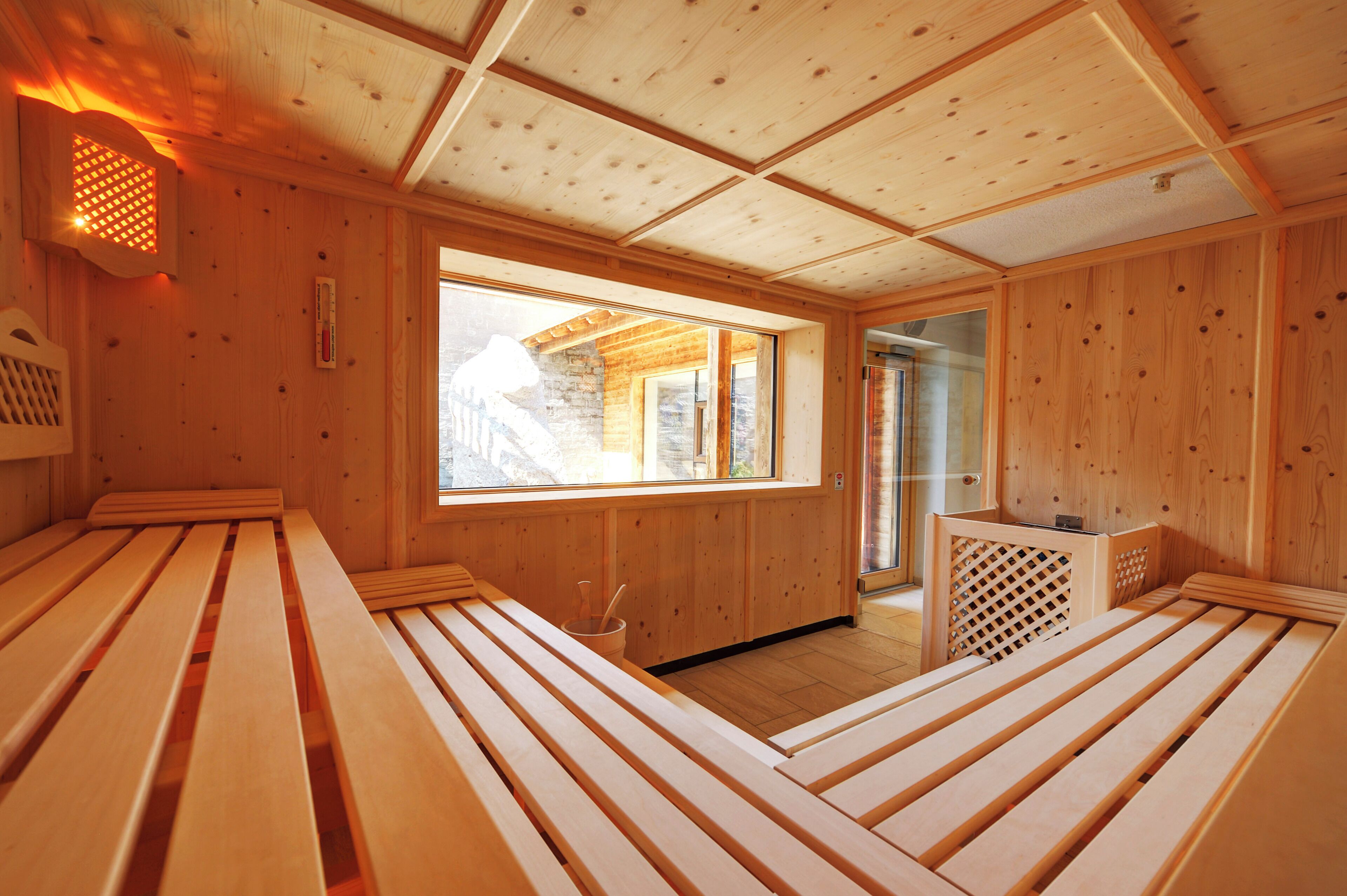 Una sauna in legno con panche e un'ampia finestra.
