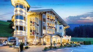 Et stort, flerlags hotel med et markant tårn, flere balkoner og et veloplyst indgangsparti.