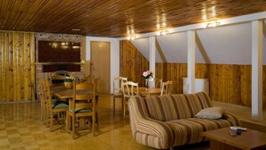 Una habitación acogedora con techo de madera, un comedor con horno de ladrillo y un sofá con cojines a rayas.