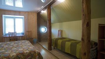 A room with a bed, a desk, and a chair. There is a window and a door.