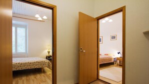 Un dormitorio con piso de madera, una cama con colcha floral, una mesita de noche con lámpara y una ventana con persianas.