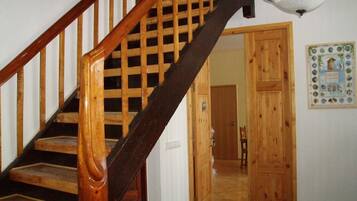 Una escalera de madera con barandal oscuro y una lámpara en la parte superior.