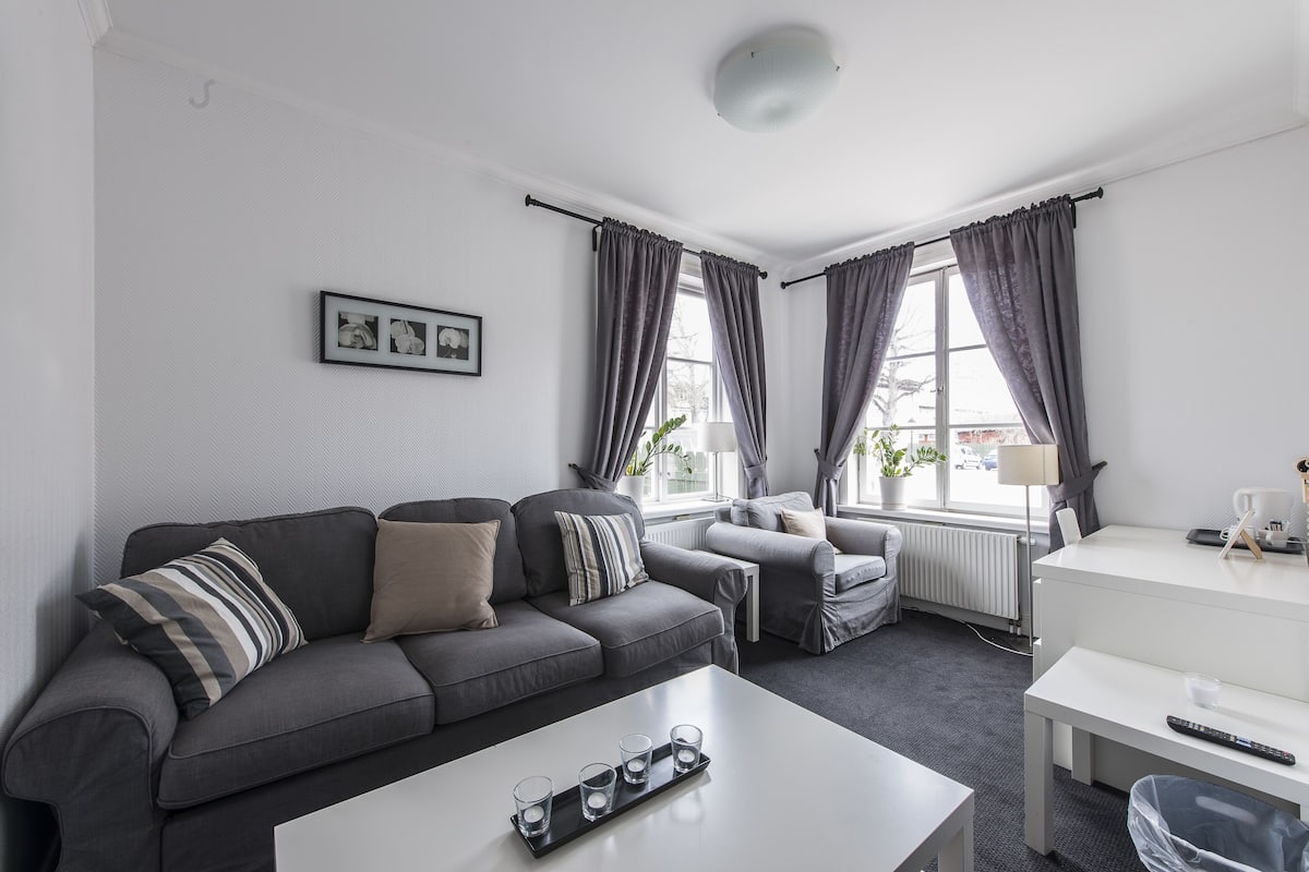 A modern living room with a grey sofa, a white coffee table, and a small white table.