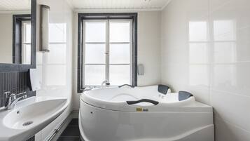 A modern bathroom with a large bathtub, a sink, and a mirror.
