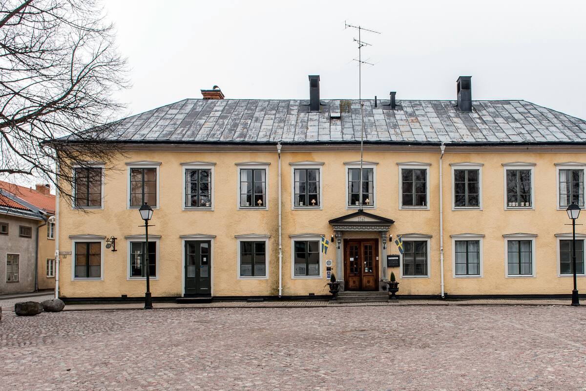 A large, yellow building with a symmetrical facade, multiple windows, and a central entrance.