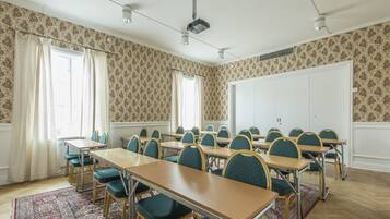 Un salón de conferencias con una mesa larga, varias sillas, un proyector y una pizarra.