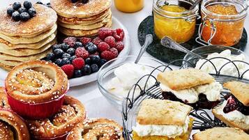 A breakfast buffet with pancakes, berries, pastries, and jams.