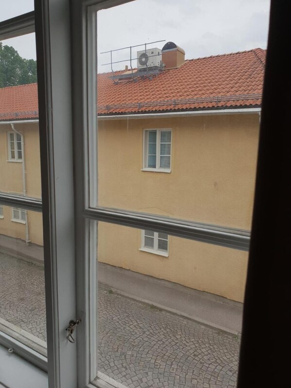 Vista desde una ventana de un edificio con tejado de tejas y fachada amarilla.
