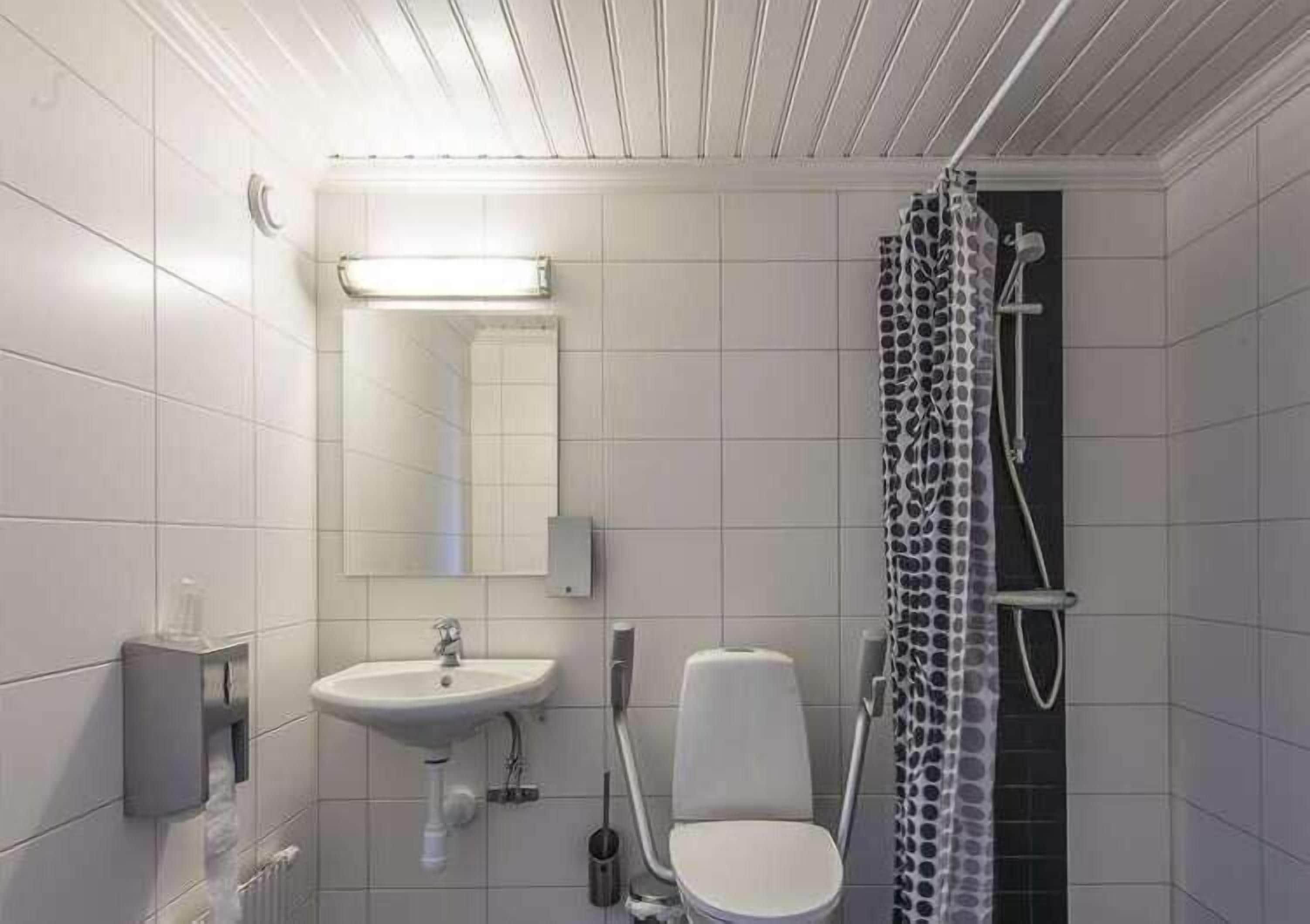 A modern bathroom with a white sink, mirror, toilet, and shower.