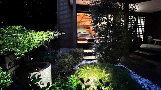 A nighttime garden pathway leading to a traditional Japanese-style room with tatami flooring and a low table. - Hananobou Kinkakuji-michi (Kyoto)
