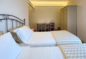 Una camera d'albergo con un letto, una scrivania e un armadio.