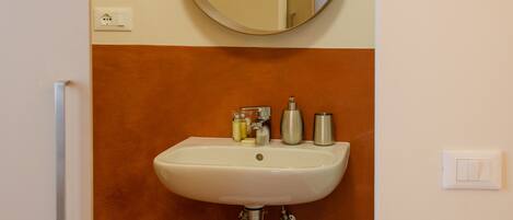 Un baño con un espejo redondo, un lavabo y un perchero para toallas.