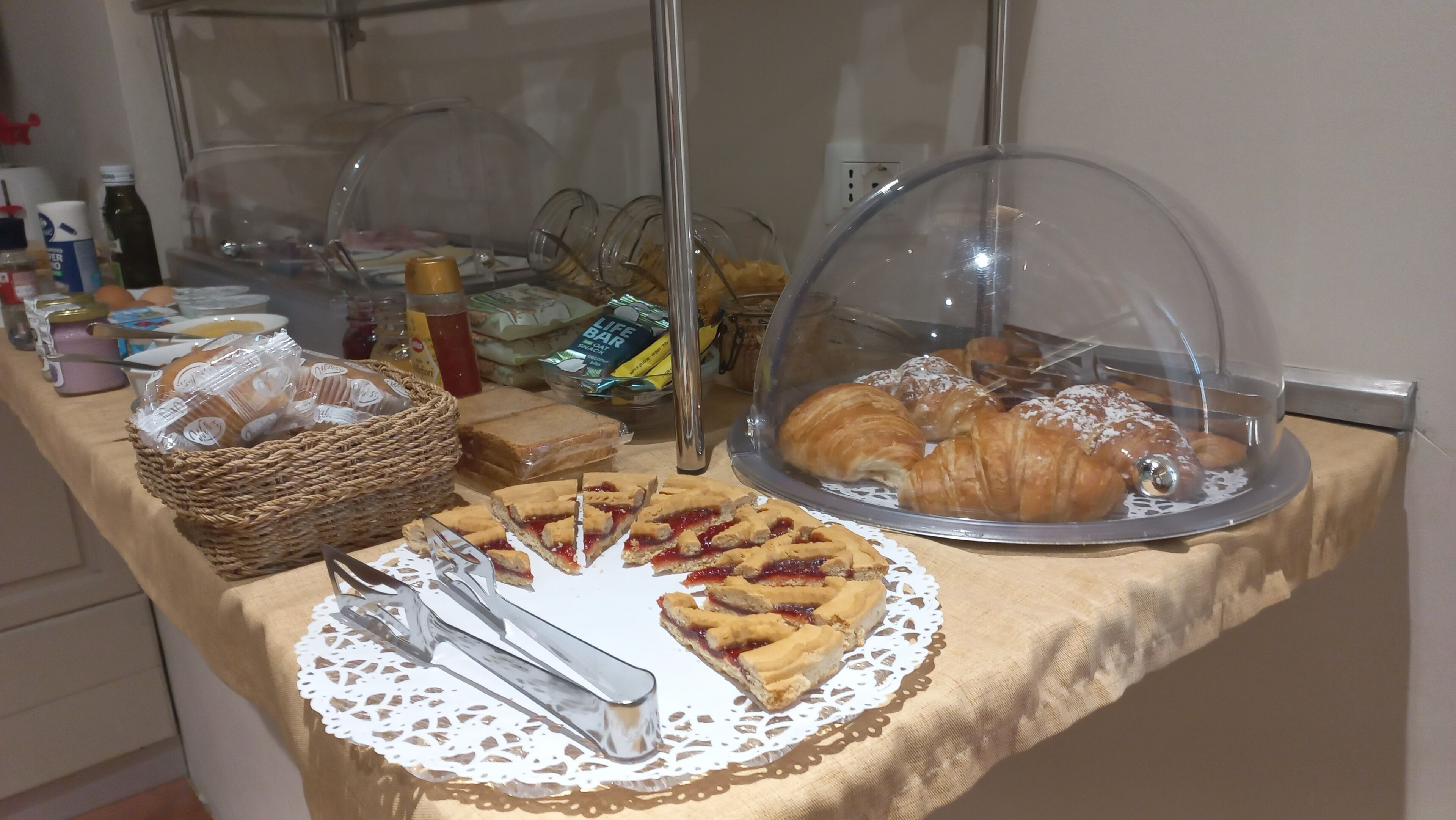 Un buffet proposant une variété de plats, notamment des pâtisseries, des sandwichs et une sélection de croissants présentée sous cloche.
