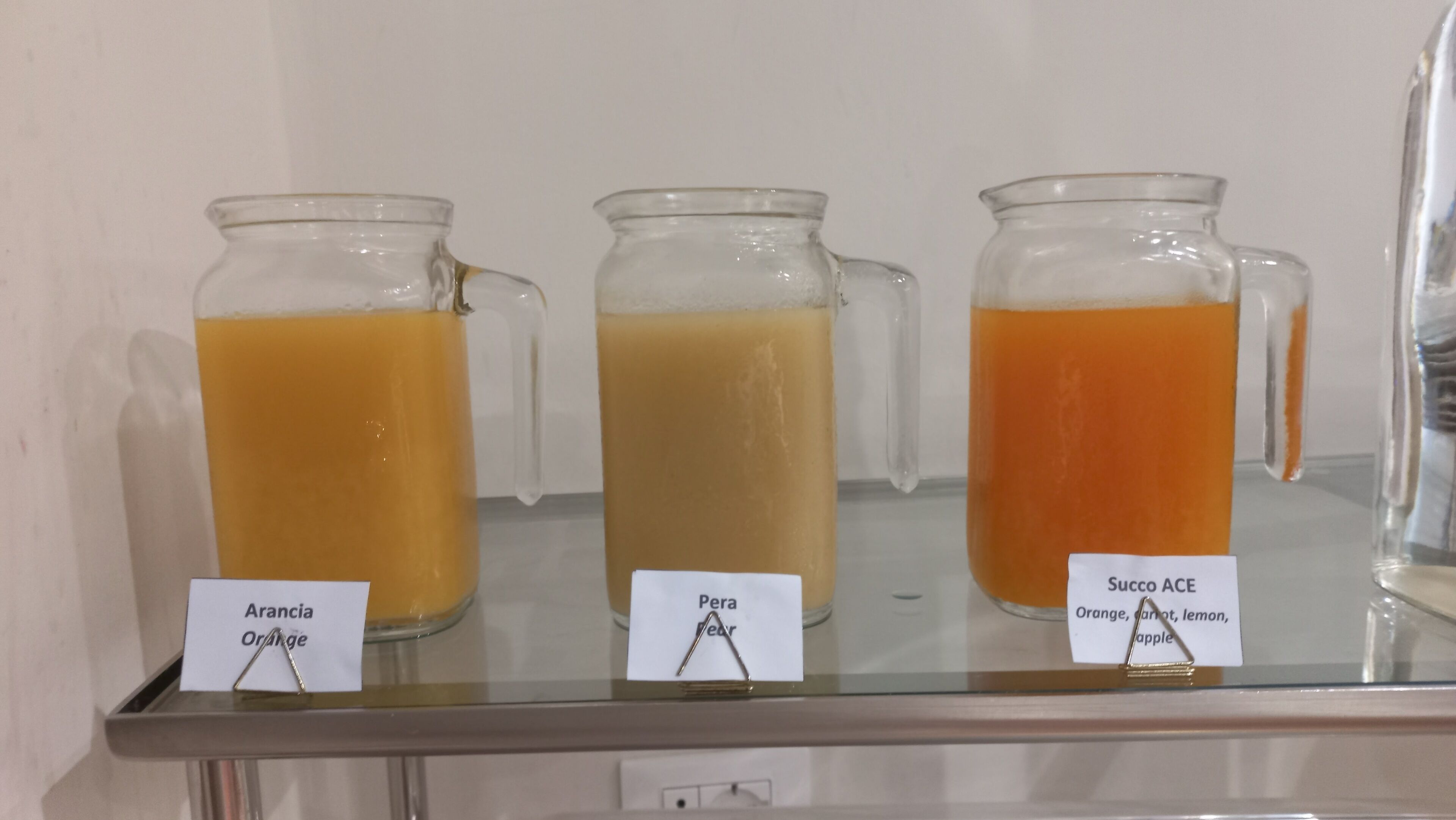 Tres tazas de vidrio con etiquetas en una estantería.