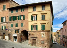 Un edificio storico con diversi piani, persiane verdi e un ingresso ben visibile.
