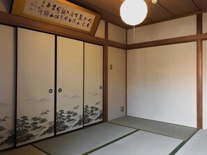 A traditional Japanese room with tatami flooring, shoji screens, and a hanging light fixture. - Hananobou Bettei (Kyoto)